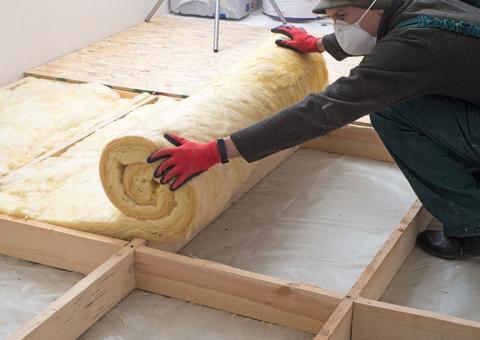 person wearing gloves rolling out insulation